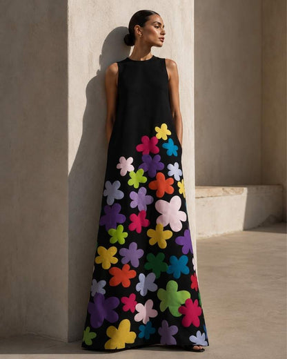 Model trägt ein schwarzes ärmelloses Maxikleid mit großen bunten Blumenapplikationen im eleganten Sommerlook.
