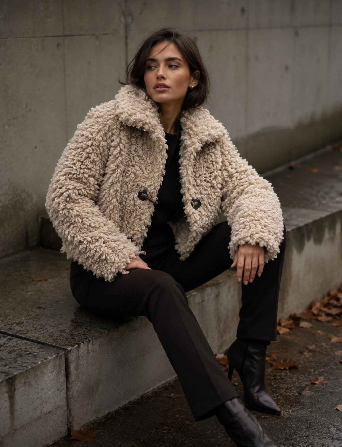 Damen Herbst Outfit mit beiger Teddyjacke, schwarzer Hose und schwarzen Stiefeletten im modernen Streetstyle