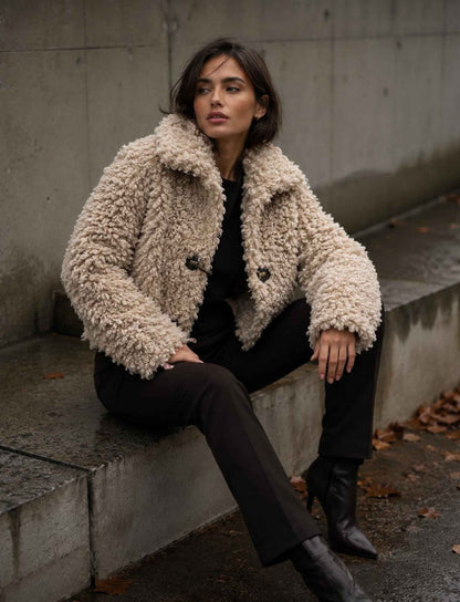 Damen Herbst Outfit mit beiger Teddyjacke, schwarzer Hose und schwarzen Stiefeletten im modernen Streetstyle