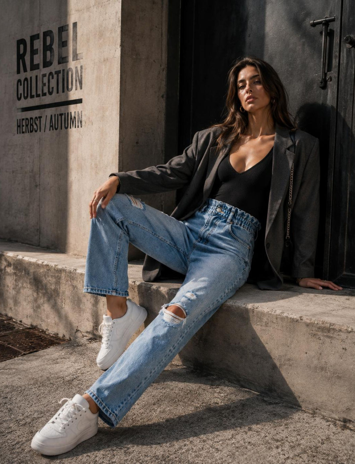 Damen Rebel Herbst Outfit mit hellblauer Destroyed Jeans, schwarzem Blazer, schwarzem Top und weißen Sneakern