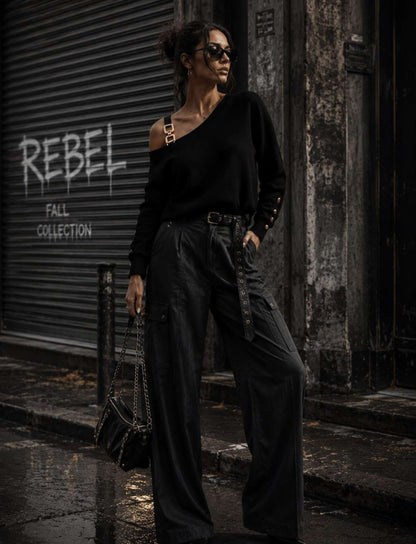 Damen Rebel Herbst Outfit mit schwarzem One Shoulder Pullover mit goldenen Details, schwarzer Wide Leg Cargohose und schwarzer Handtasche