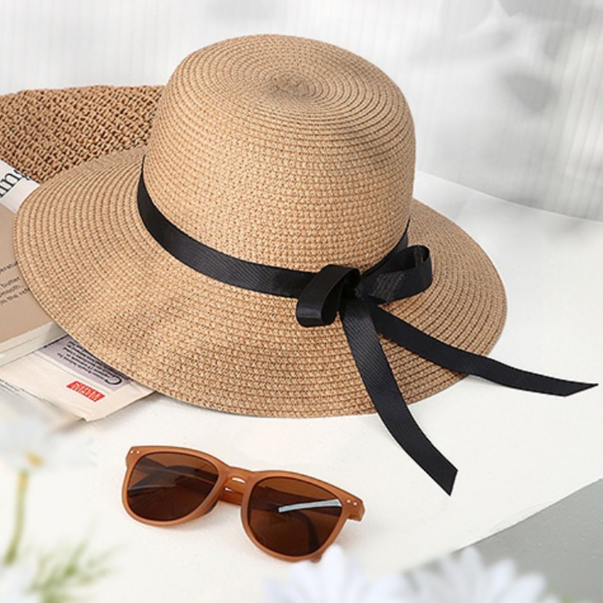 Damen Strohhut mit schwarzer Schleife und breiter Krempe auf Tisch mit Sonnenbrille, sommerliches Accessoire