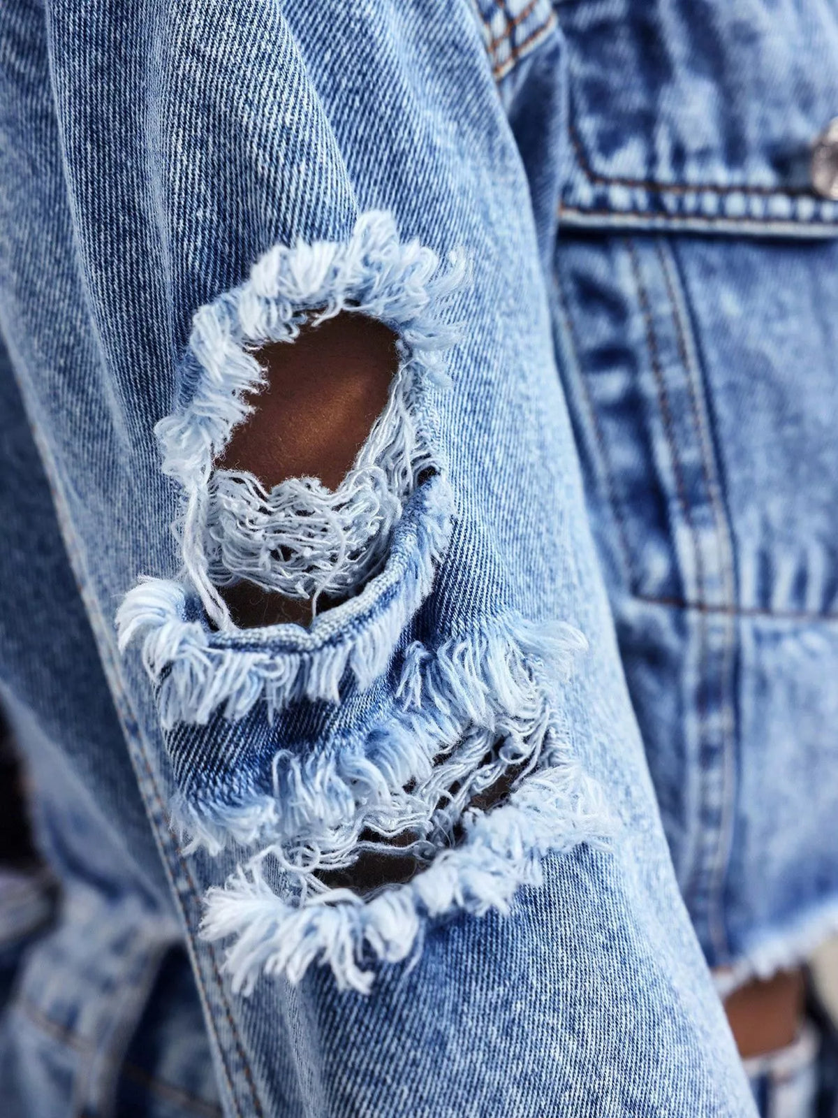 Detailansicht der ausgefransten Destroyed-Partie an der Cropped Jeansjacke für Damen