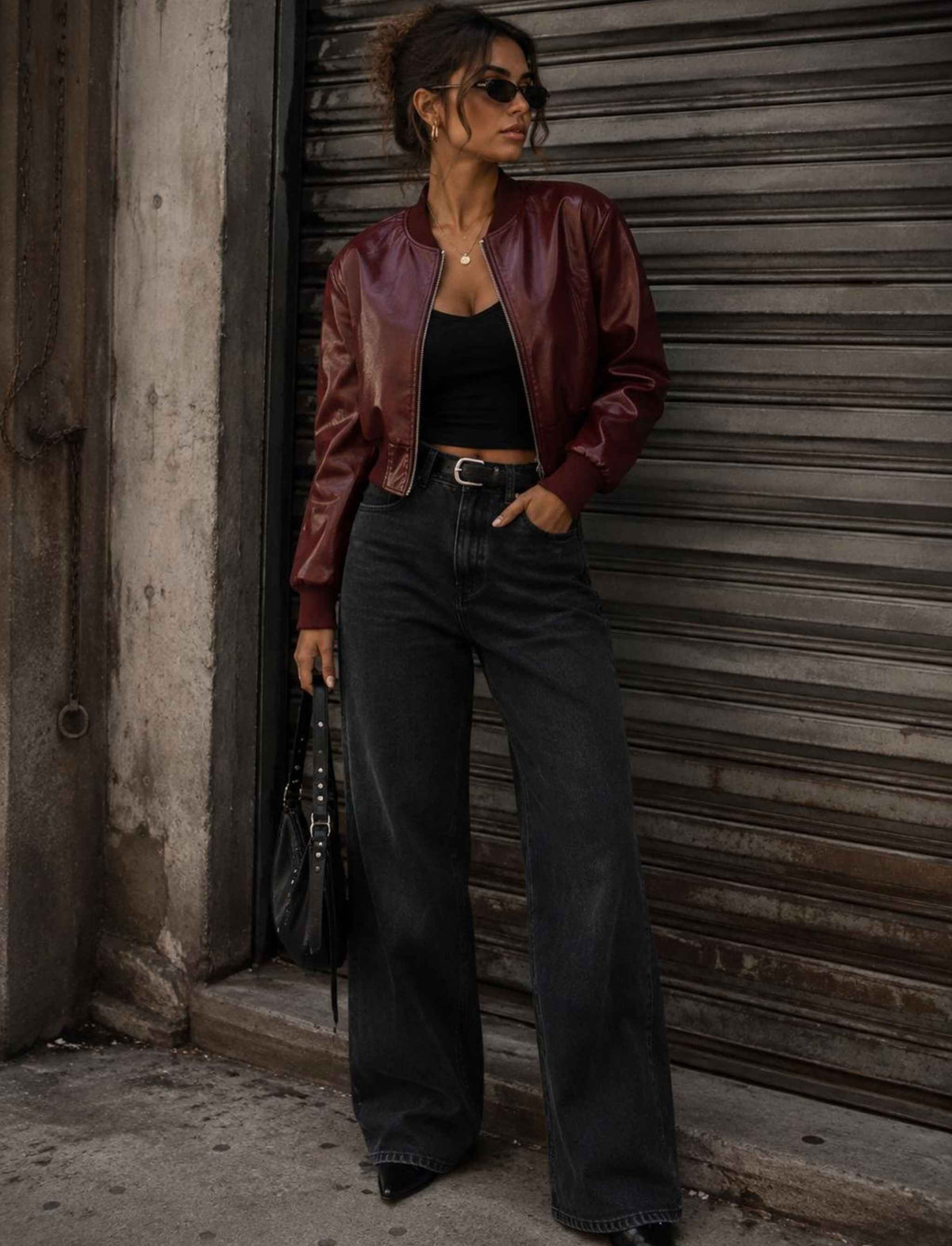 Bordeauxrote Cropped-Kunstlederjacke für Damen kombiniert mit schwarzem Top und schwarzer Wide-Leg-Jeans im herbstlichen Rebel Streetstyle