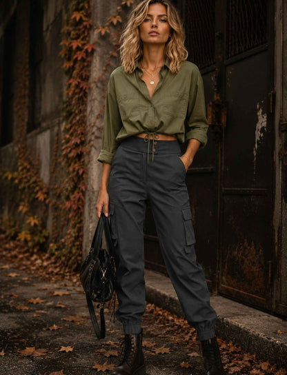 Graue Cargo-Joggerhose für Damen mit hoher Taille und Seitentaschen kombiniert mit khakifarbener Bluse und schwarzen Boots im herbstlichen Rebel Streetstyle