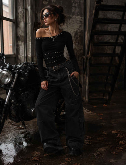 Schwarzes One-Shoulder Top für Damen mit langen Ärmeln und Nieten kombiniert mit schwarzer Wide-Leg-Cargohose im Rebel Streetstyle