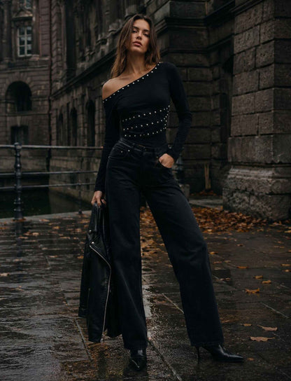Schwarzes One-Shoulder Top für Damen mit langen Ärmeln und Nieten kombiniert mit schwarzer Wide-Leg-Hose im herbstlichen Rebel Streetstyle