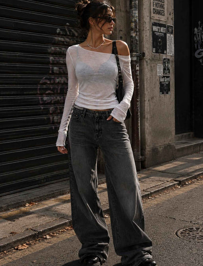 Weißes transparentes Langarm-Top für Damen im Off-Shoulder-Look kombiniert mit grauer Wide-Leg-Jeans im Rebel Streetstyle