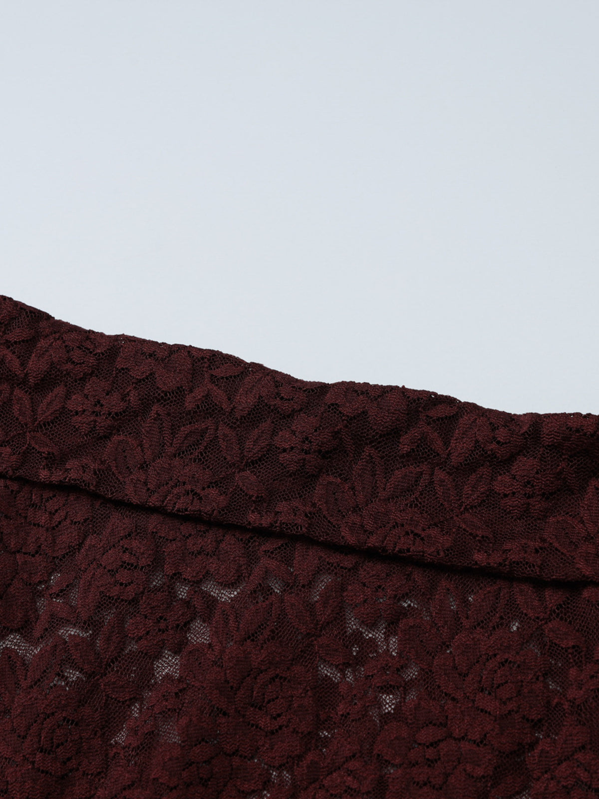 Nahaufnahme des floralen Spitzenstoffs des asymmetrischen Damen-Langarmtops
